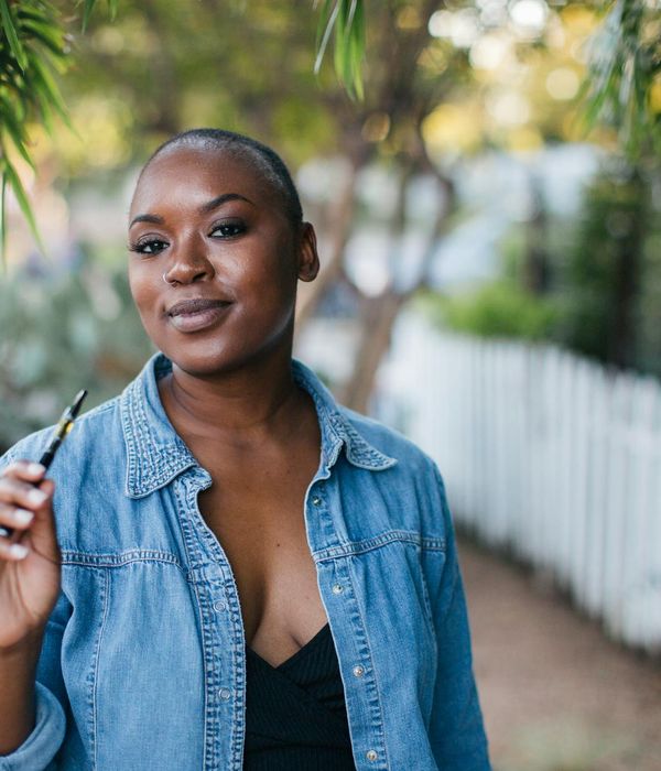 Person smiling and looking serene outdoors in a natural setting.