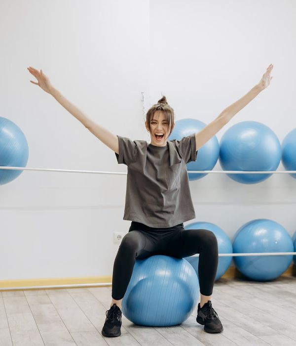 Woman performing a gentle stretching exercise in a bright room.
